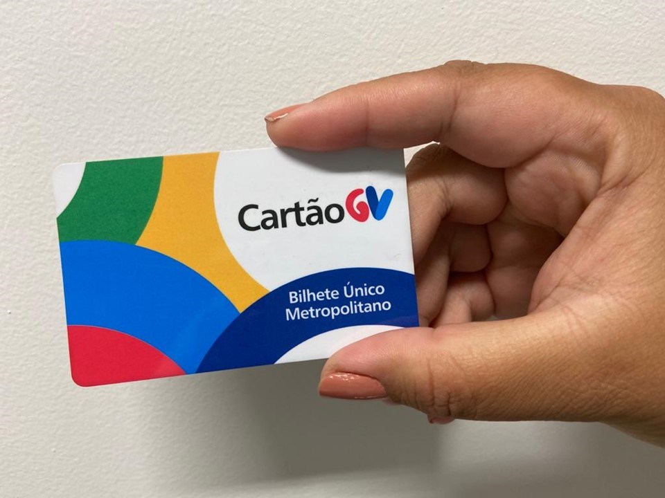 Visão aproximada do cartão de transporte azul do Sistema Transcol sobre uma superfície neutra.