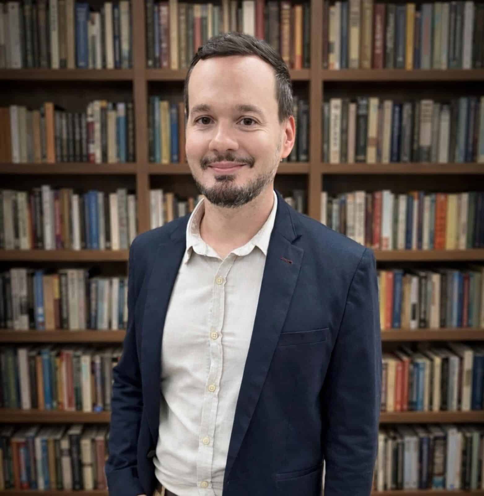 Retrato do economista André Spalenza, coordenador do Connect Fecomércio-ES, com uma estante de livros ao fundo.