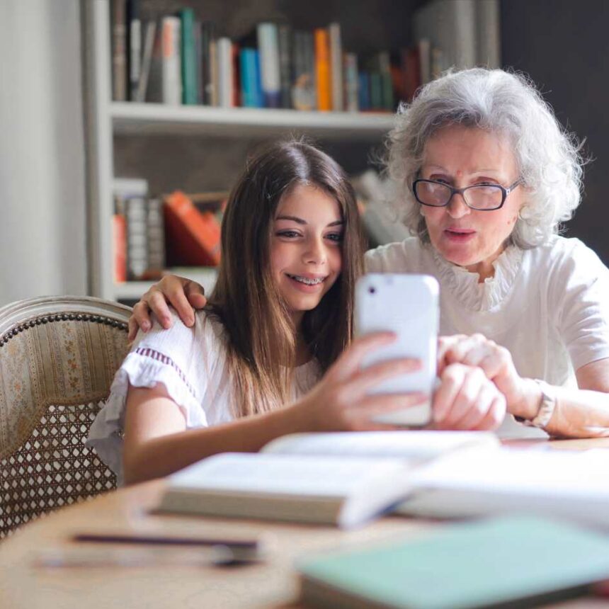 Senhora e neta idosa segurando um iPhone travado na mão, buscando como forçar o desligamento do iPhone.