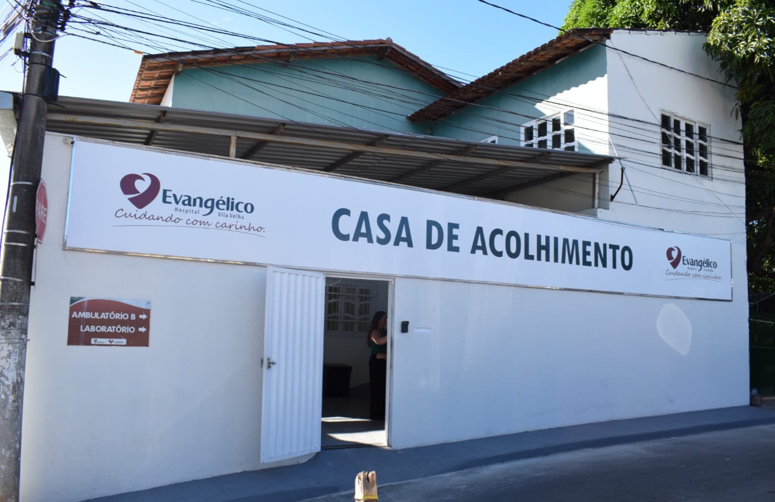 Fachada da Casa de Acolhimento do Hospital Evangélico de Vila Velha, com placa de identificação e logomarca.
