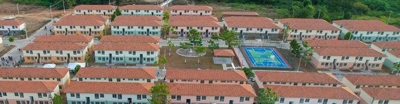 Vista aérea ou frontal de um condomínio com várias casas populares geminadas e organizadas, representando o setor de habitação e construção civil dentro da Engrenagem da Prosperidade Capixaba.