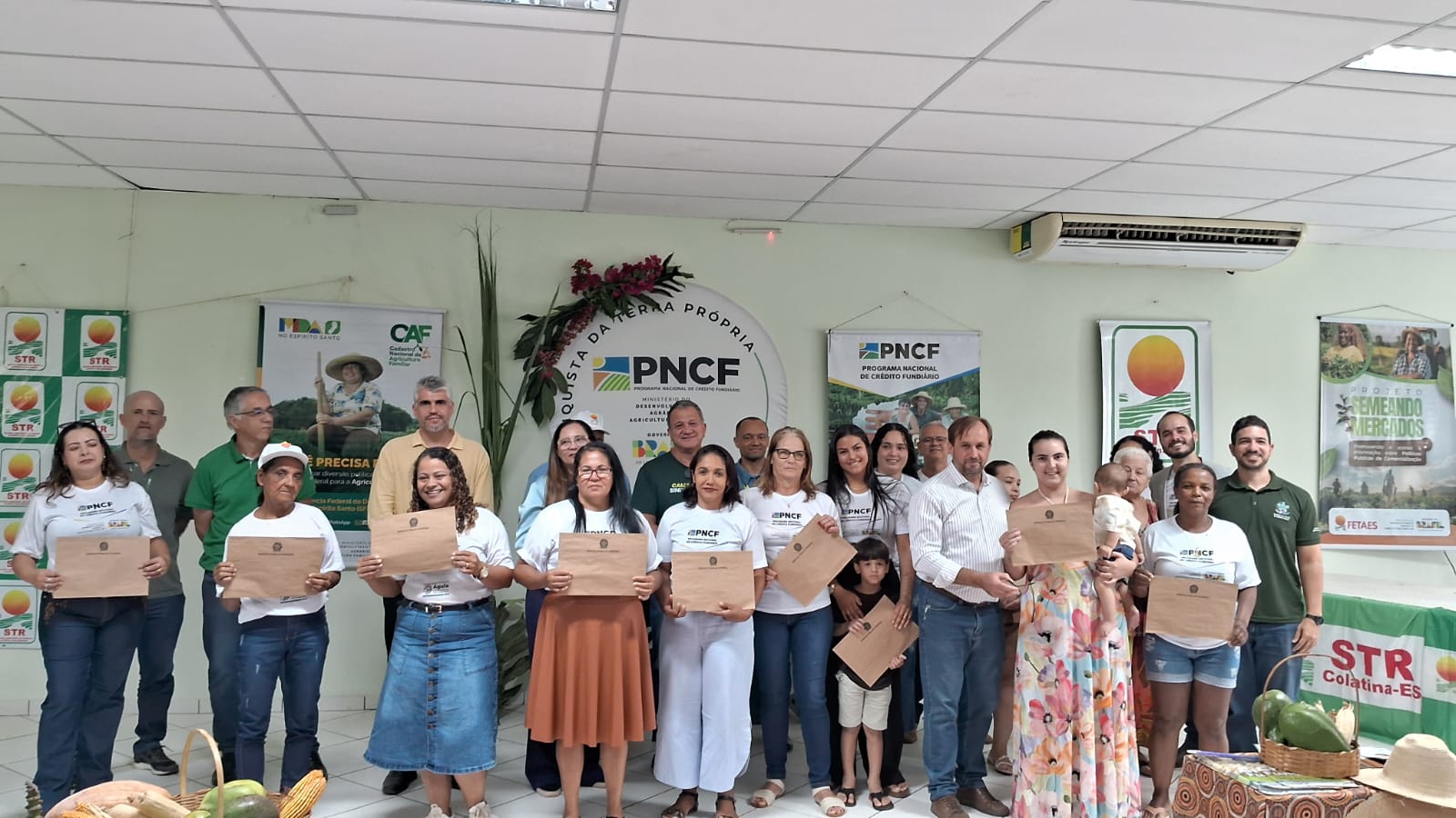 Família agricultora sorrindo ao receber escritura de terra em Colatina.