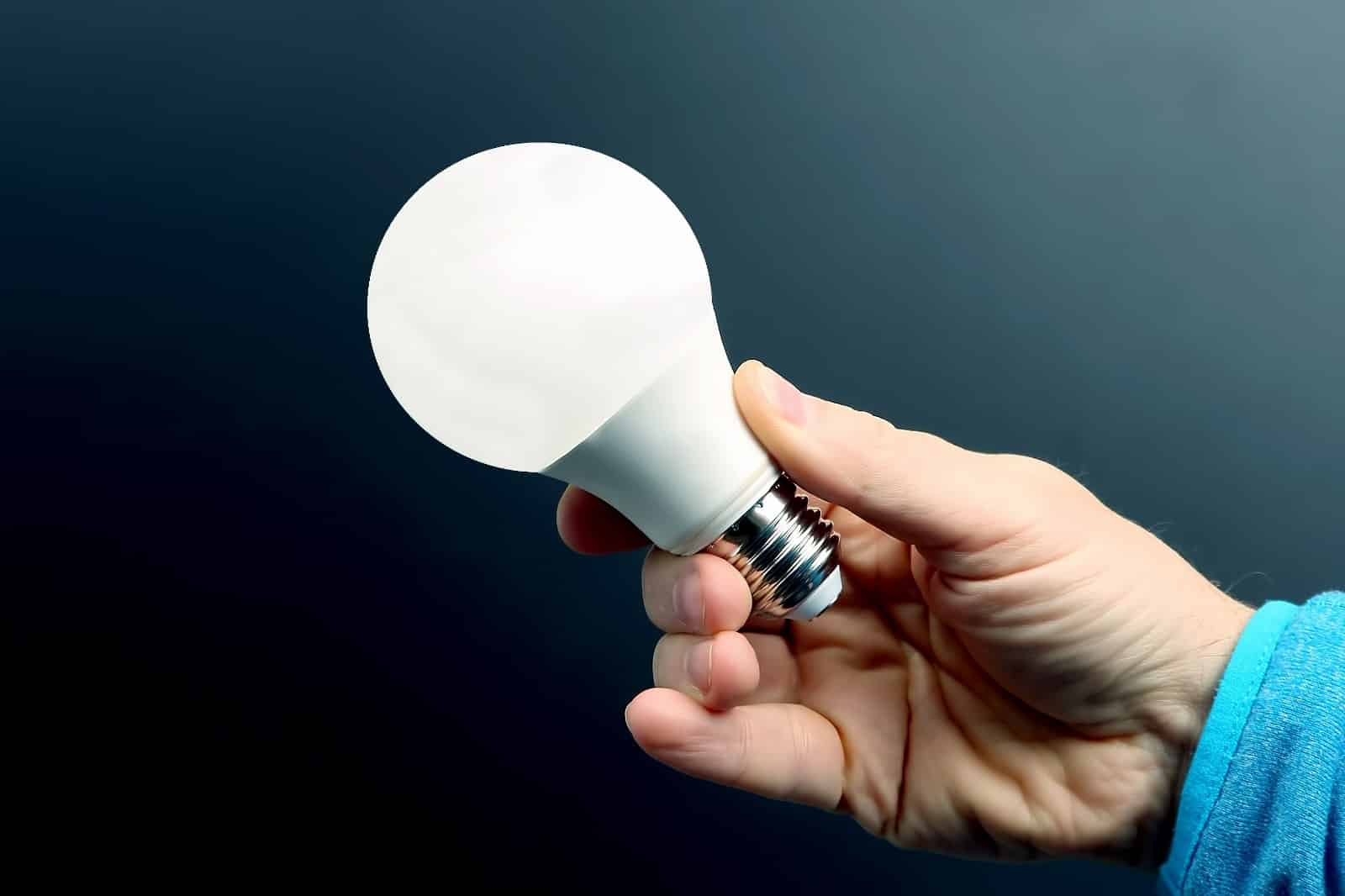 Mão segurando conta de luz da EDP e celular com site da Tarifa Social.