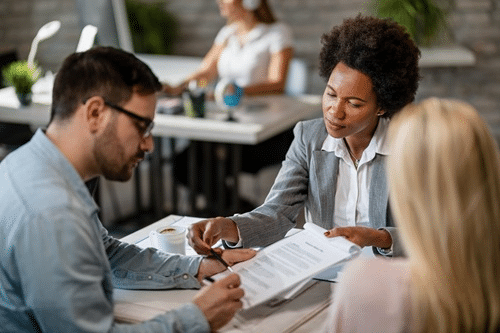 Fotografia em ambiente corporativo iluminado mostrando as mãos de um microempresário capixaba assinando um contrato de renegociação financeira sobre uma mesa de escritório, simbolizando as facilidades da campanha Pra Quitar do Bandes, em destaque no portal Informe Capixaba.