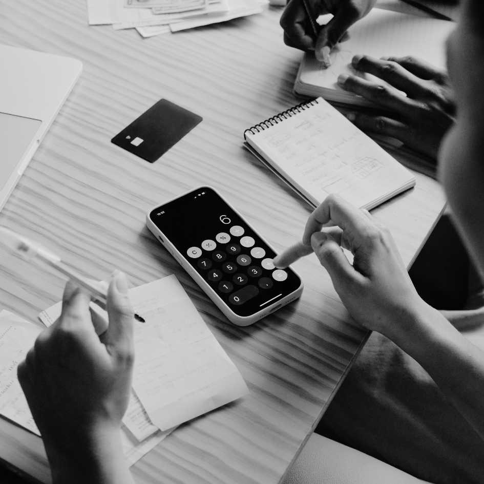 Pessoa utilizando calculadora em mesa com diversos papéis e documentos para análise de dados da FINDES.
