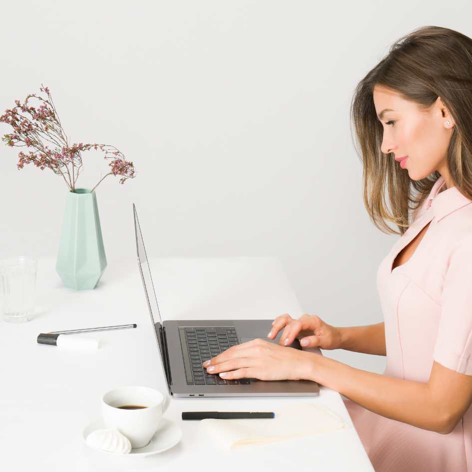 Jovem mulher calmamente digitando em frente ao computador, com foco total para superar a ilusão do dinheiro fácil "Betes" e construir sua carreira.