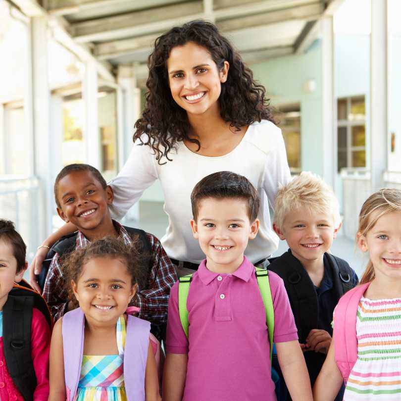 Curso de Cuidadora Infantil em Presidente Kennedy: Mulher segurando livro infantil ao lado de uma criança em ambiente escolar.