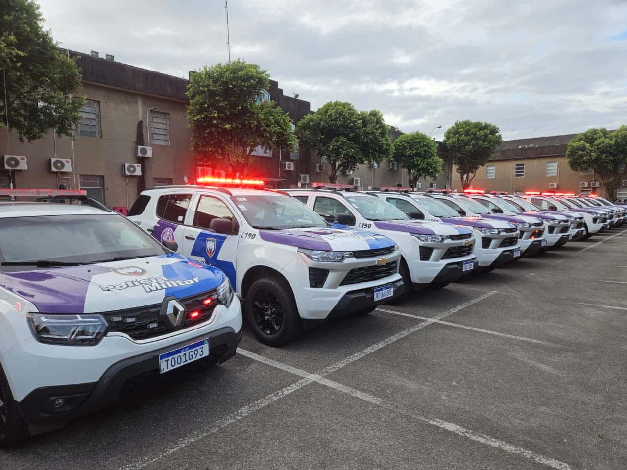 Viaturas modernas da Polícia Militar com grafismo lilás para atendimento a ocorrências de violência doméstica.