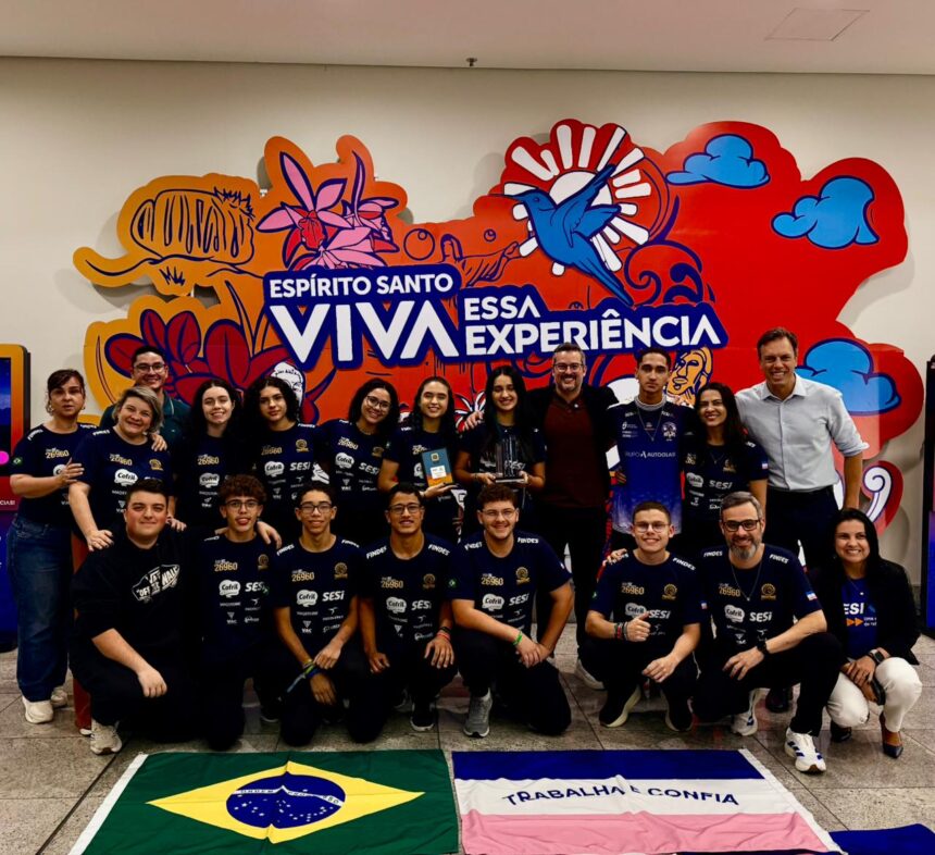 Alunos do SESI ES segurando troféu e bandeira do Brasil em competição internacional de robótica nos Estados Unidos.
