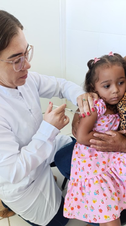 Enfermeira preparando dose de vacina infantil em uma sala de vacinação limpa e organizada.