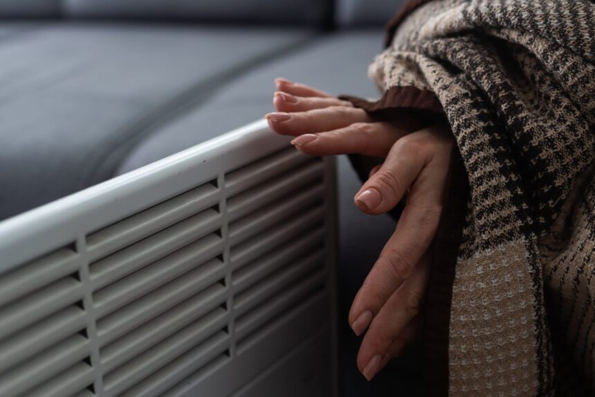 Mão regulando aparelho doméstico para reduzir a conta de luz no inverno de forma eficiente.