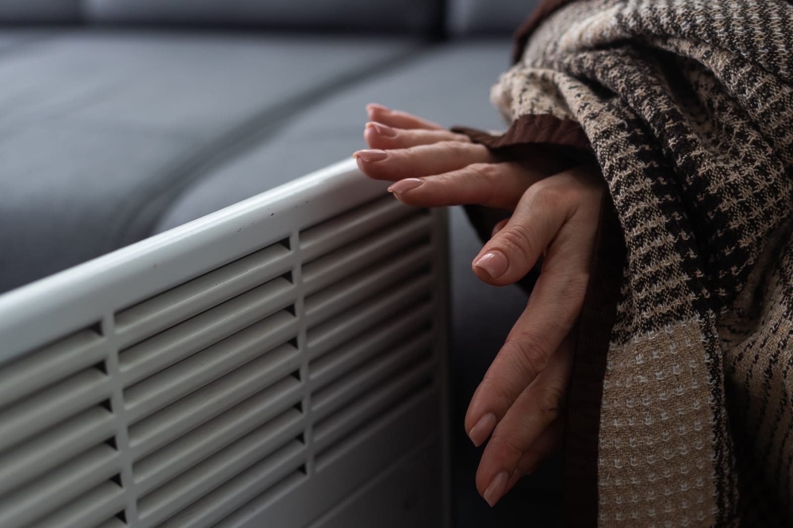 Mão regulando aparelho doméstico para reduzir a conta de luz no inverno de forma eficiente.