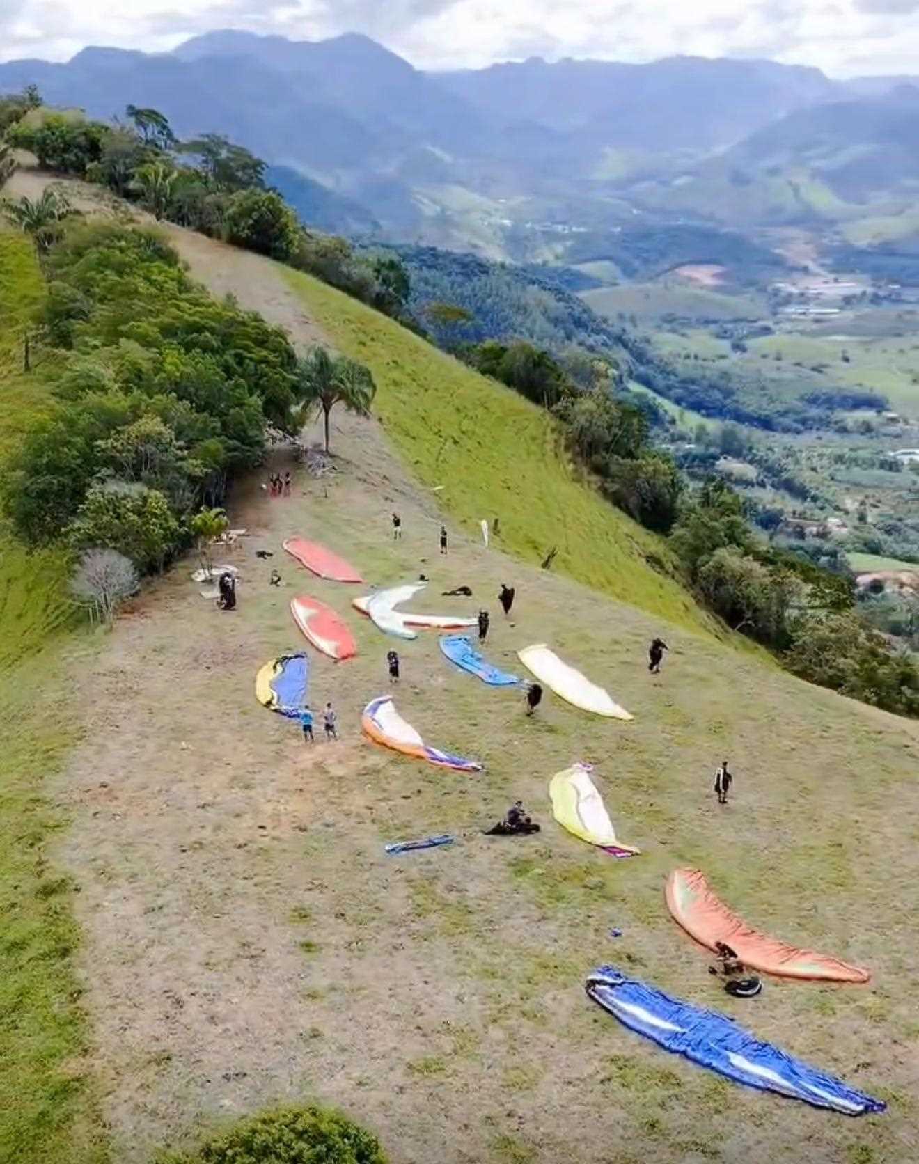 Céu de Alfredo Chaves coberto por asas de parapente coloridas durante as baterias do campeonato Super Open Paragliding 2026 nas montanhas do Espírito Santo.