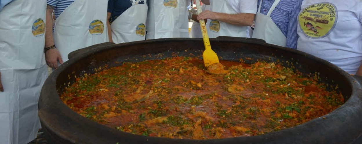 Cozinheiros preparando a maior moqueca do mundo em uma panela de barro gigante no cais de Conceição da Barra durante festival da culinária capixaba.