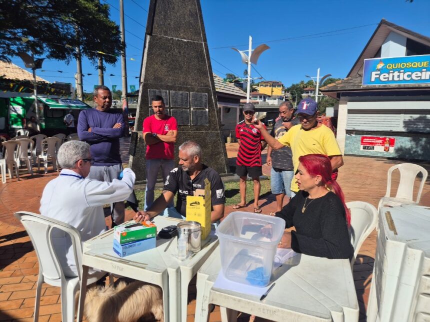 Profissional de saúde aplicando vacina no braço de um homem adulto dentro de uma estrutura de atendimento móvel.