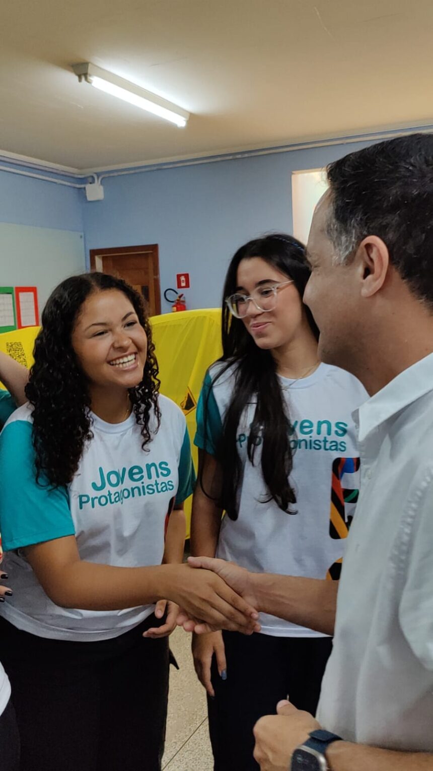 Foto com foco no deputado Gandini conversando com estudantes da rede estadual que vestem os novos uniformes escolares azuis.