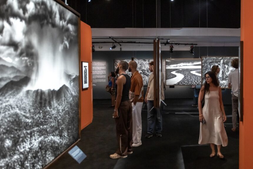 Visitantes apreciando fotografias de grande formato em preto e branco em uma famosa exposição cultural.