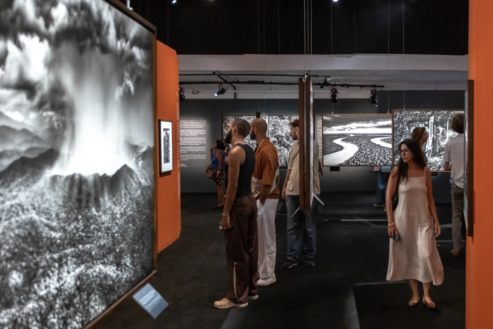 Visitantes apreciando fotografias de grande formato em preto e branco em uma famosa exposição cultural.