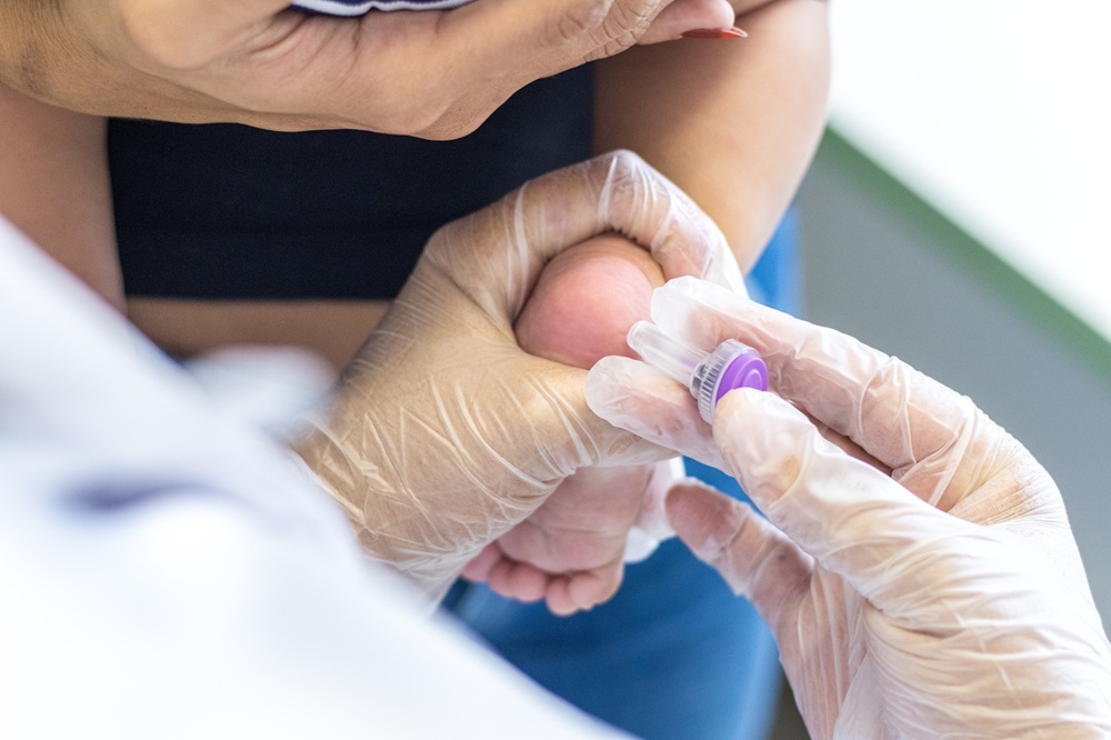 Coleta de sangue no calcanhar de um bebê para a realização do Teste do Pezinho pelo SUS.