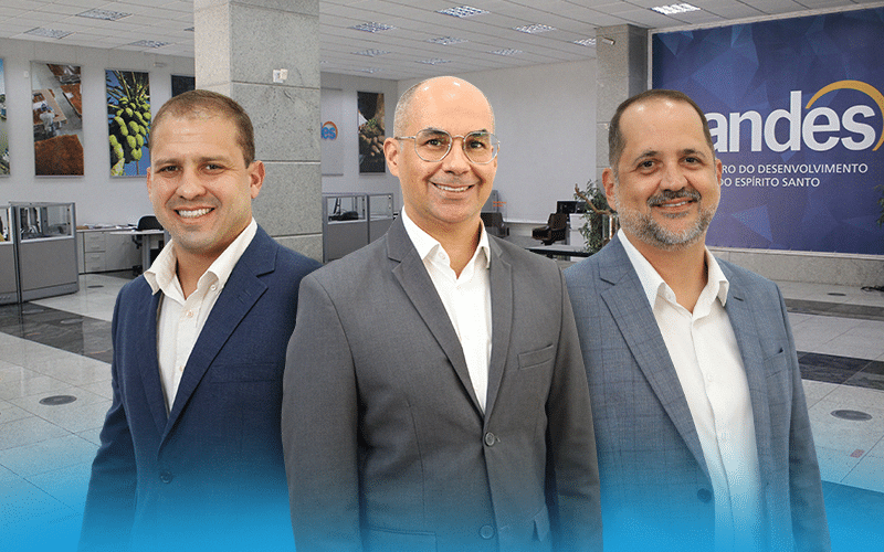Gerente de negócios em ambiente corporativo conversando de forma consultiva com empreendedores sobre linhas de crédito e desenvolvimento regional.
