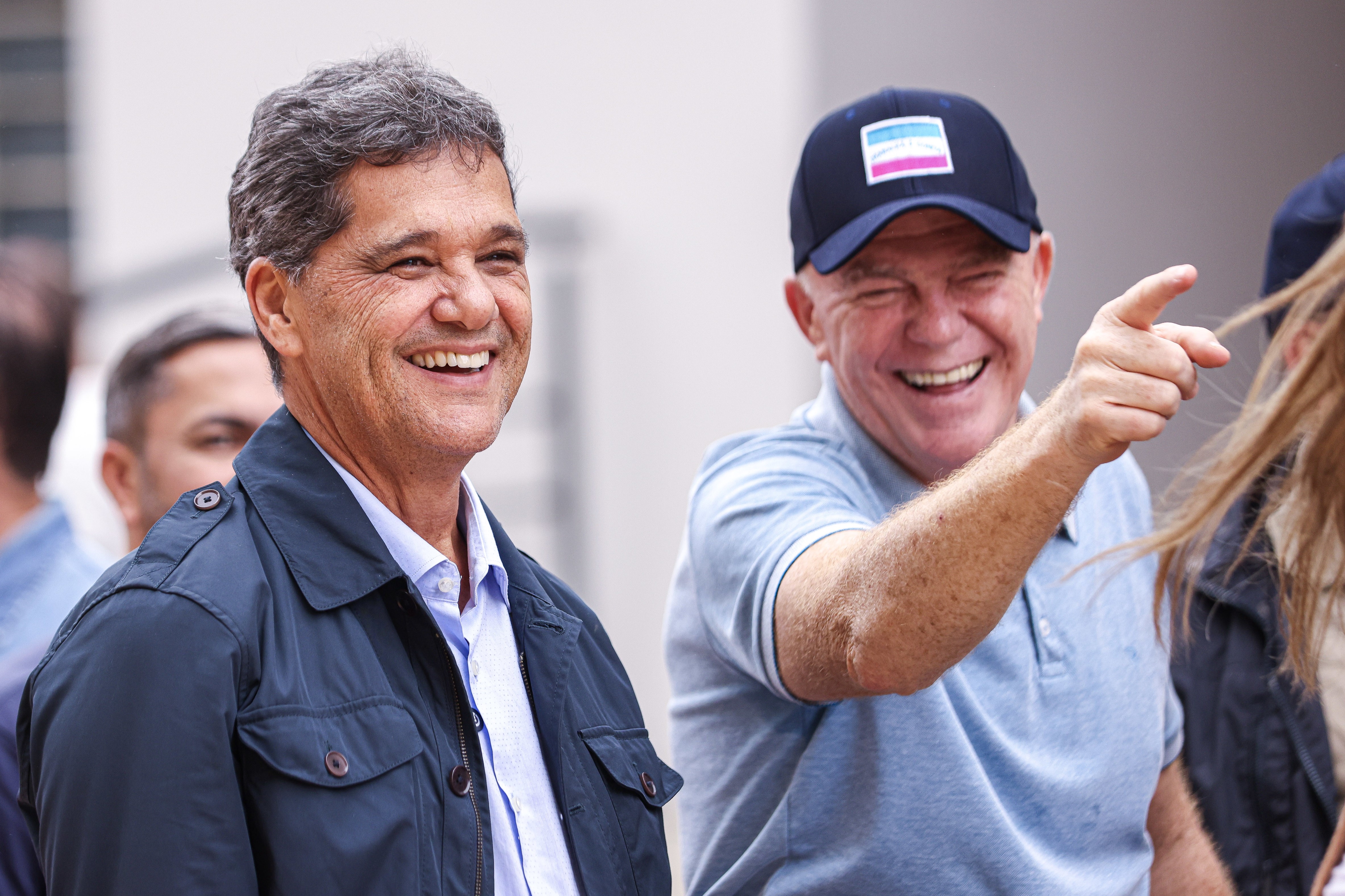 O Governador Ricardo Ferraço ao lado de Renato Casagrande sorrindo e olhando na direção em que Casagrande está apontando.
