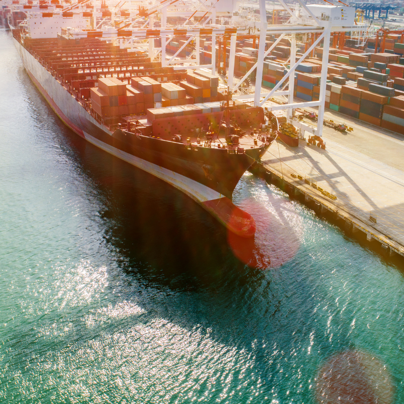 Navio de carga carregando contêineres em porto industrial voltado para as exportações do Espírito Santo.