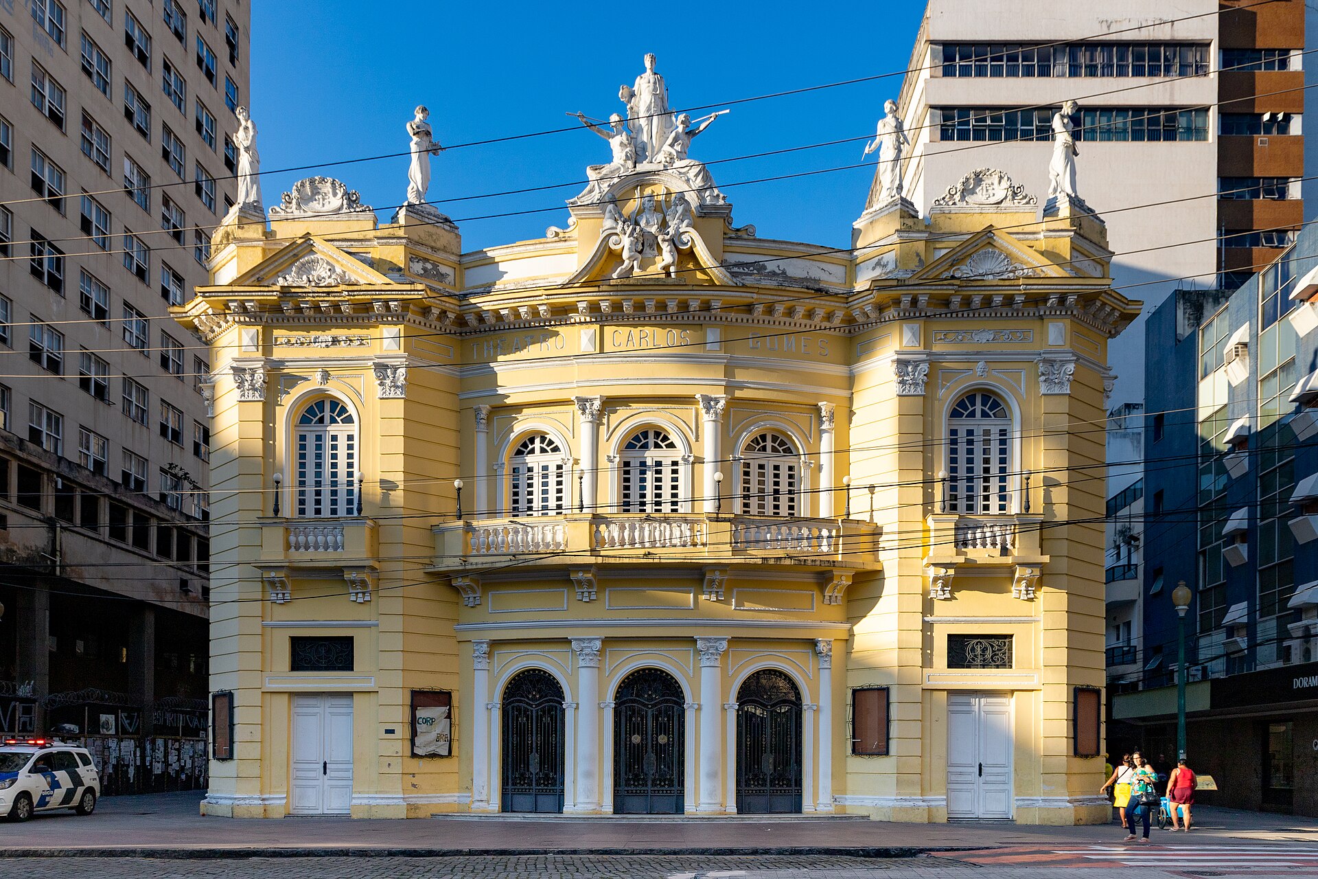 Fachada histórica do Theatro Carlos Gomes iluminada ou palco principal durante apresentação orquestral.
