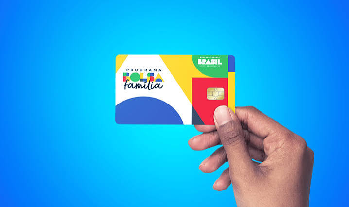 Beneficiária segurando o cartão do Bolsa Família de Agosto em frente ao caixa eletrônico.