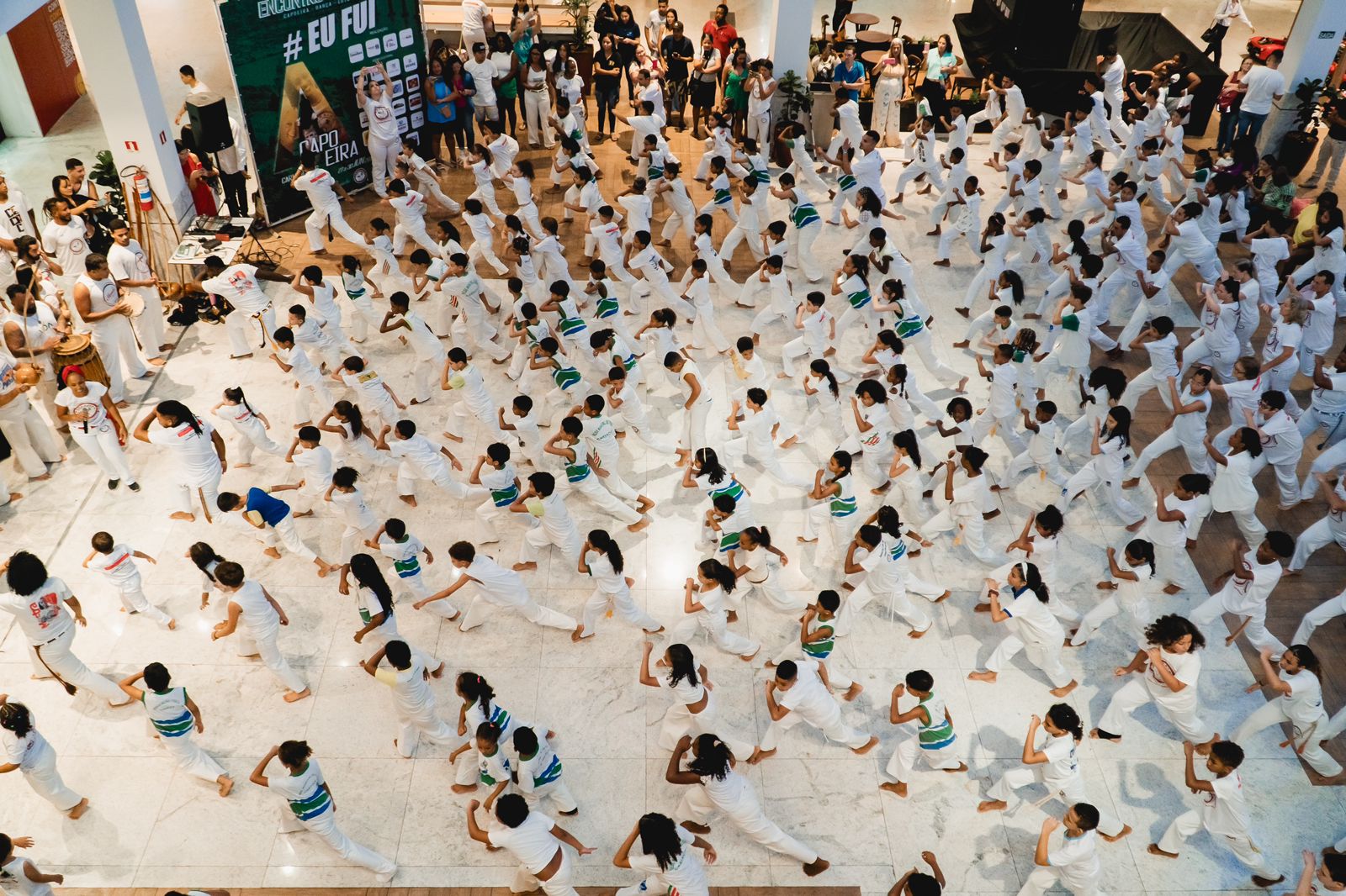 Fotografia oficial de praticantes em roda de capoeira, Mestra Baixinha em atividade educacional ou apresentação da Banda Fanfacongo na APAE Cariacica.