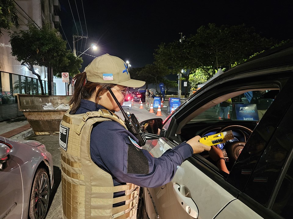 Agente de trânsito segurando etilômetro durante fiscalização das regras da Lei Seca 2026 em via pública.